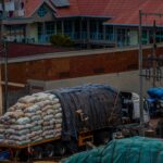 A cargo truck loaded with sacks parked in an urban area near a guest house.